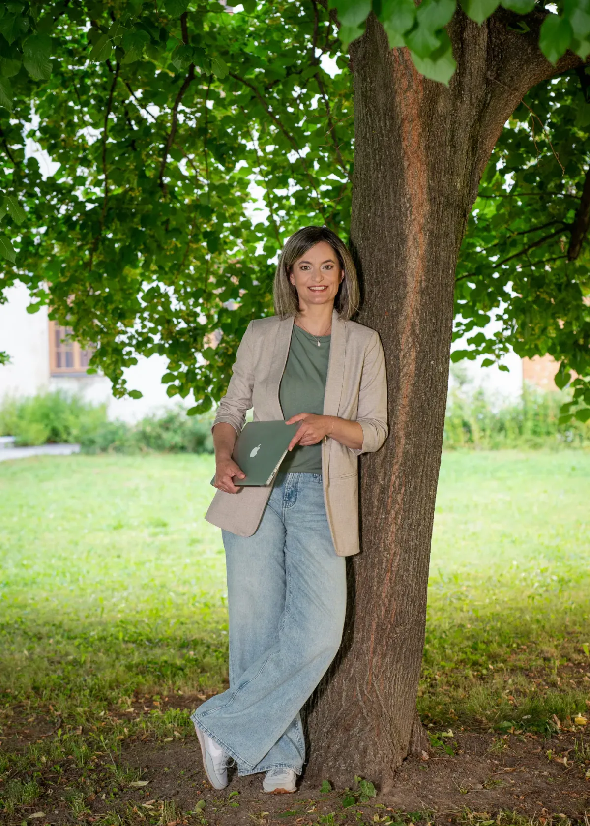Christa Rameder an einen Baum gelehnt, mit Notizbuch